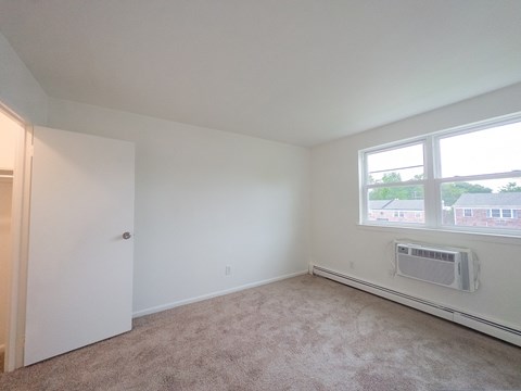 A room with a carpet floor, a window, and a door.