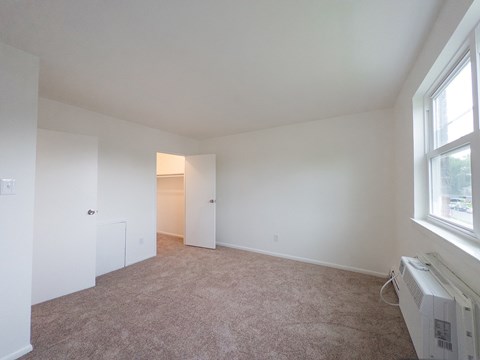 A room with a carpeted floor and a window.