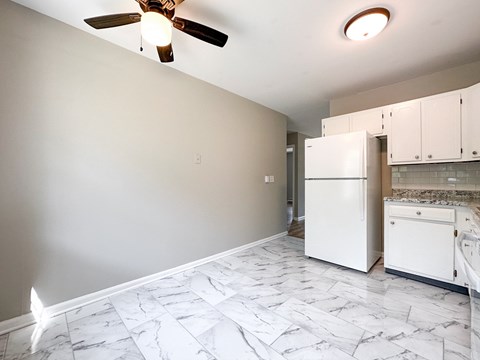 A kitchen with white cabinets and a marble floor.