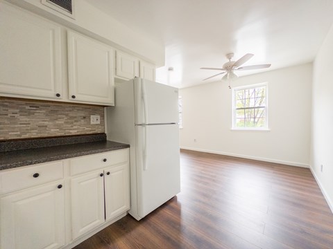A kitchen with white cabinets and a refrigerator.
