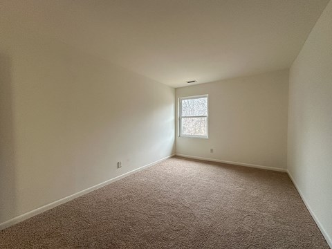 A room with a carpeted floor and a window.