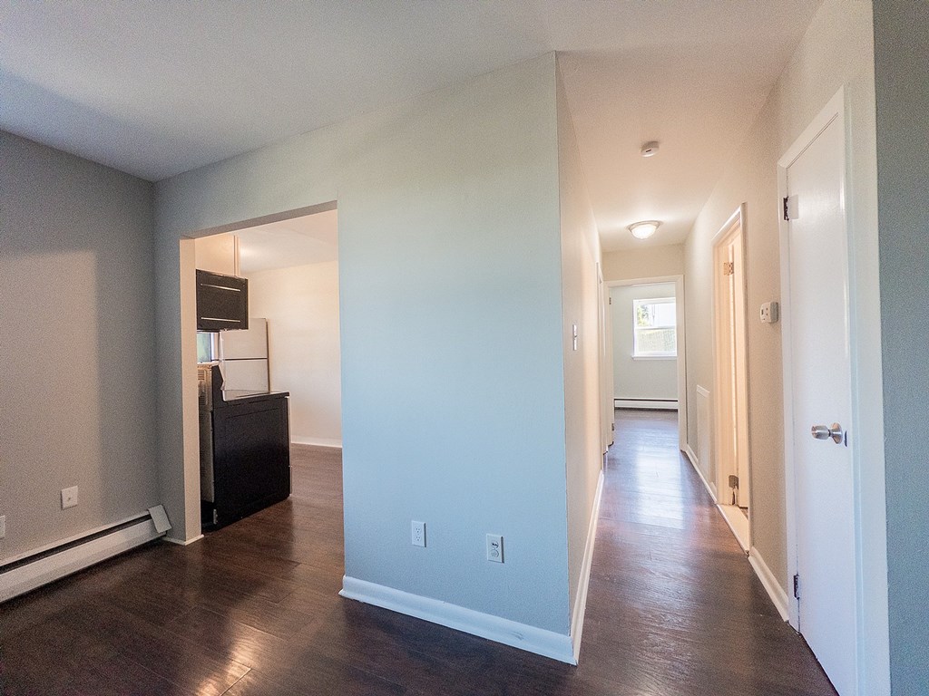 A long hallway with a door on the right and a cabinet on the left.