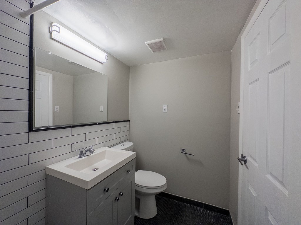 A bathroom with a toilet, sink, and mirror.
