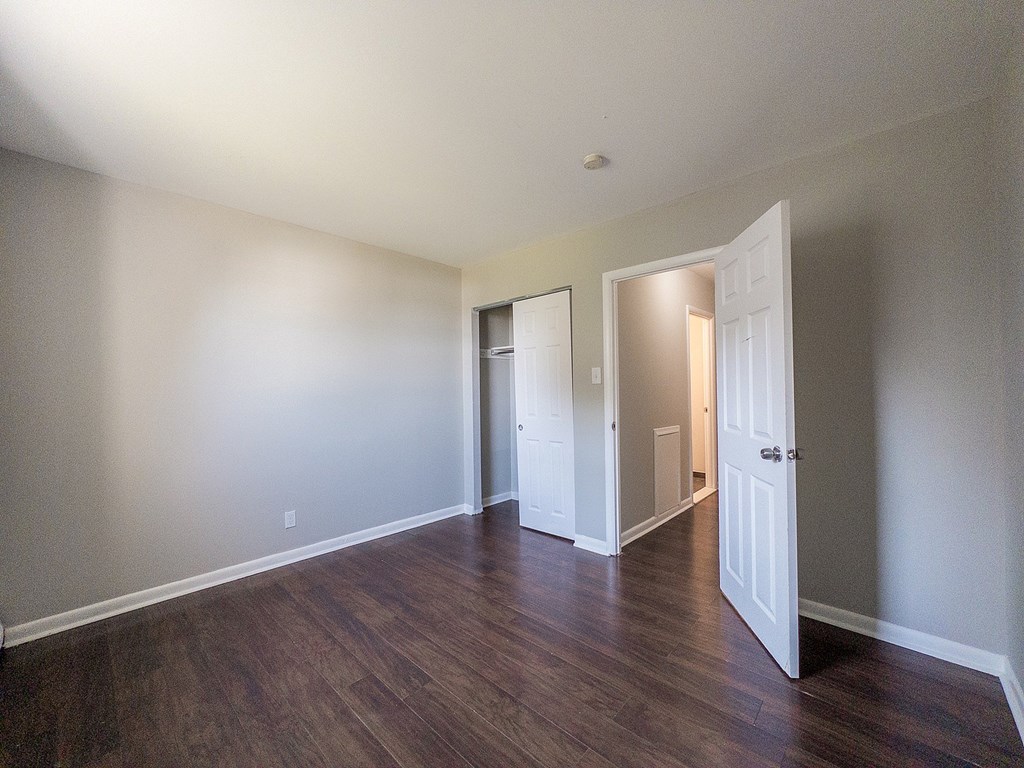 A room with white walls and wood flooring with two doors.