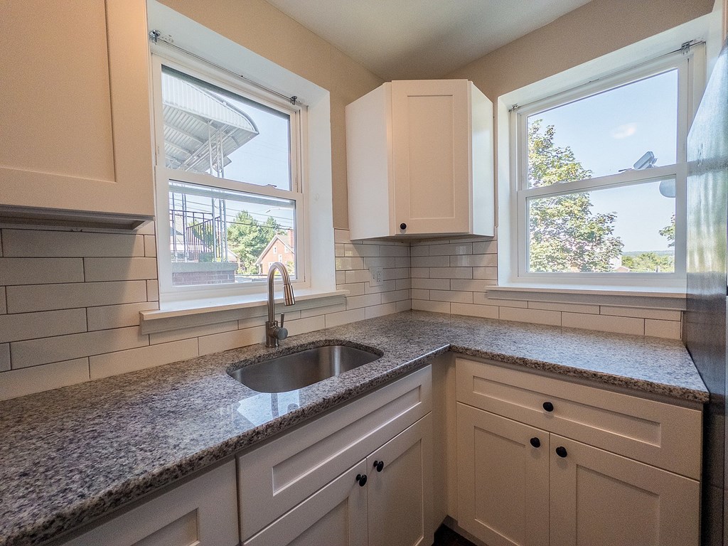 A kitchen with a granite countertop and white cabinets.