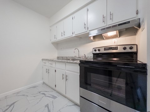 A kitchen with a black stove top oven and white cabinets.