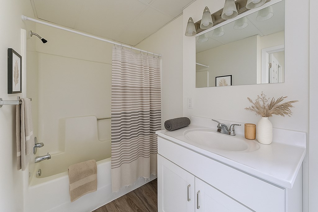 A white bathroom with a sink, mirror, and shower.