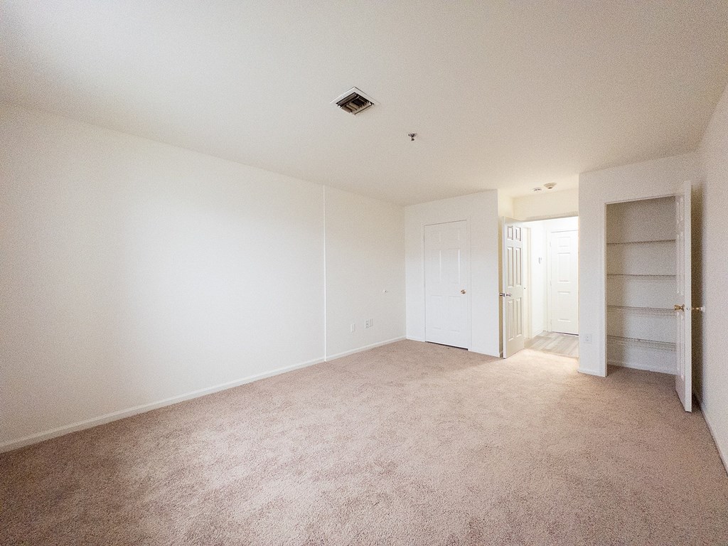 A room with a wooden floor and a window with blinds.