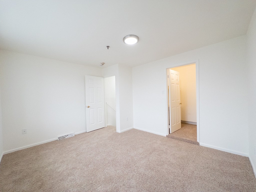A white bathroom with a toilet, sink, and mirror.