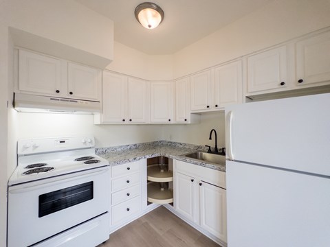 A kitchen with white cabinets and a white refrigerator.
