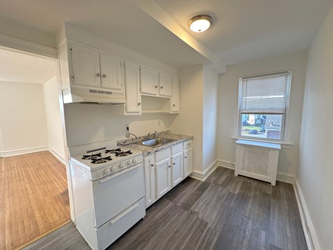 A kitchen with white cabinets and a stove top oven.