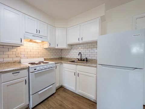 A kitchen with white appliances and cabinets.