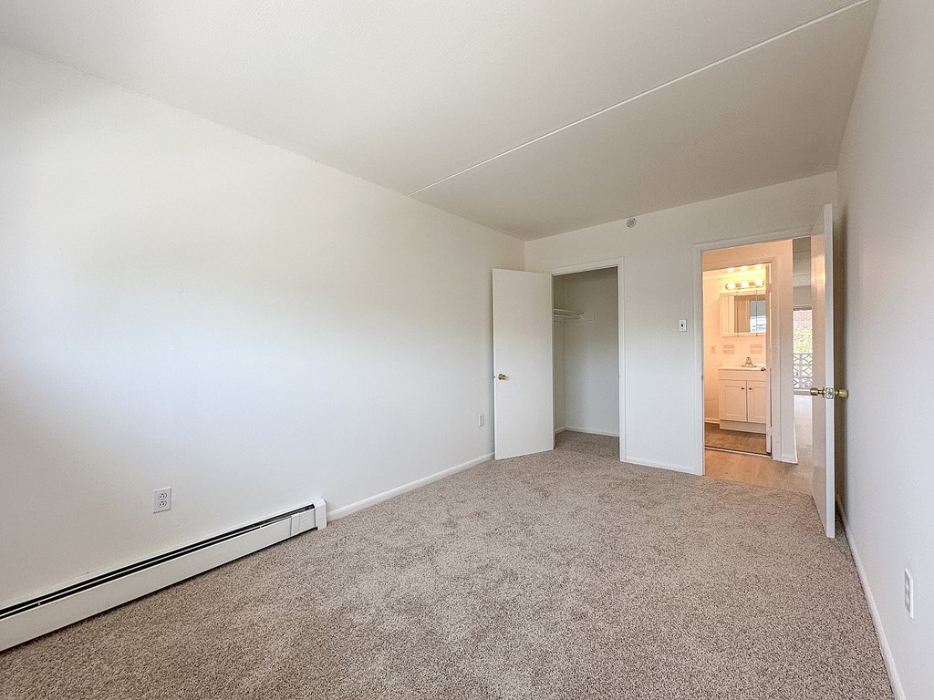 A carpeted room with a doorway leading to another room.