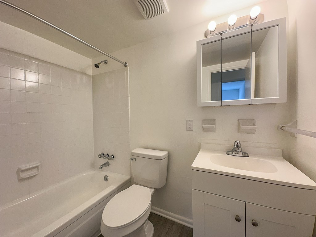 A white bathroom with a toilet, sink, and bathtub.