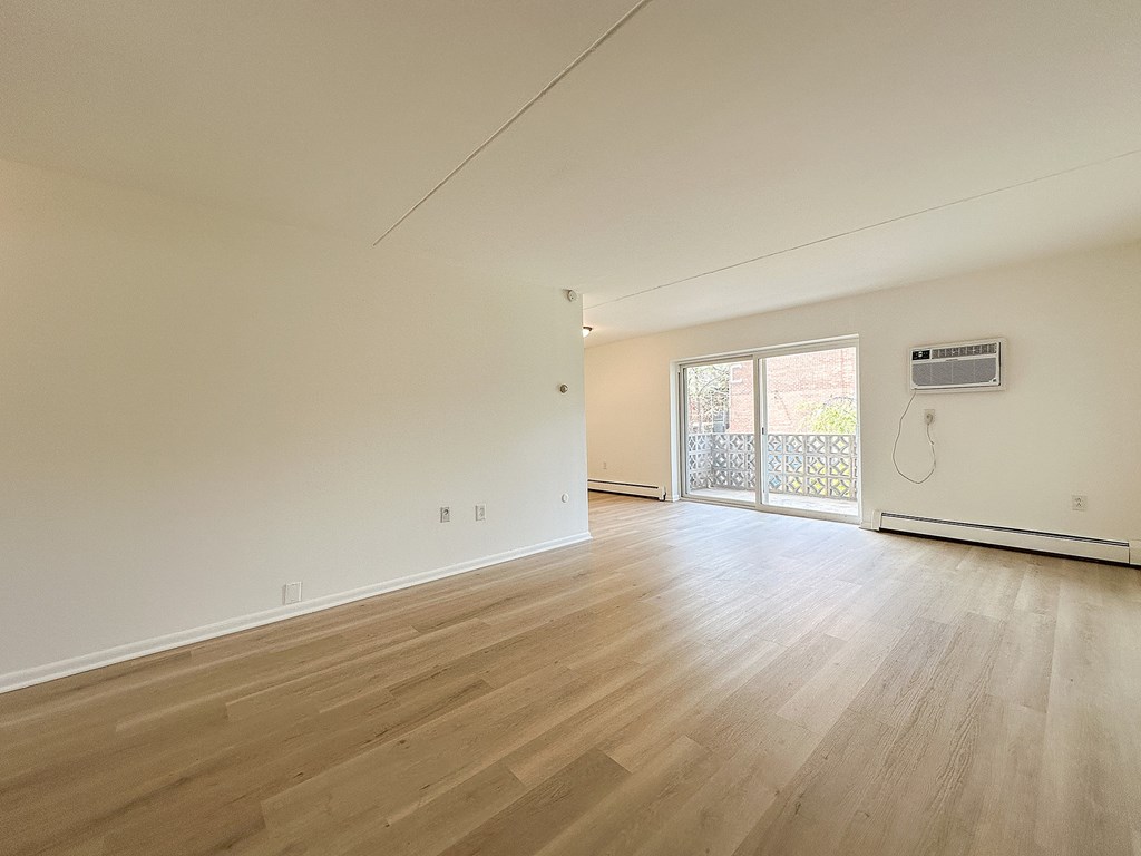 A room with wooden flooring and a sliding glass door.