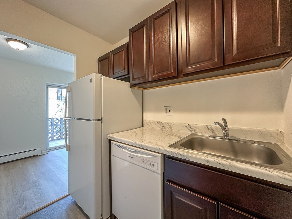 A kitchen with brown cabinets and a white fridge.