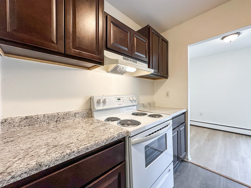 A kitchen with a white stove top oven and a white microwave above it.