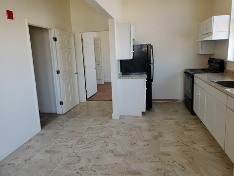 A kitchen with a black fridge and white cabinets.