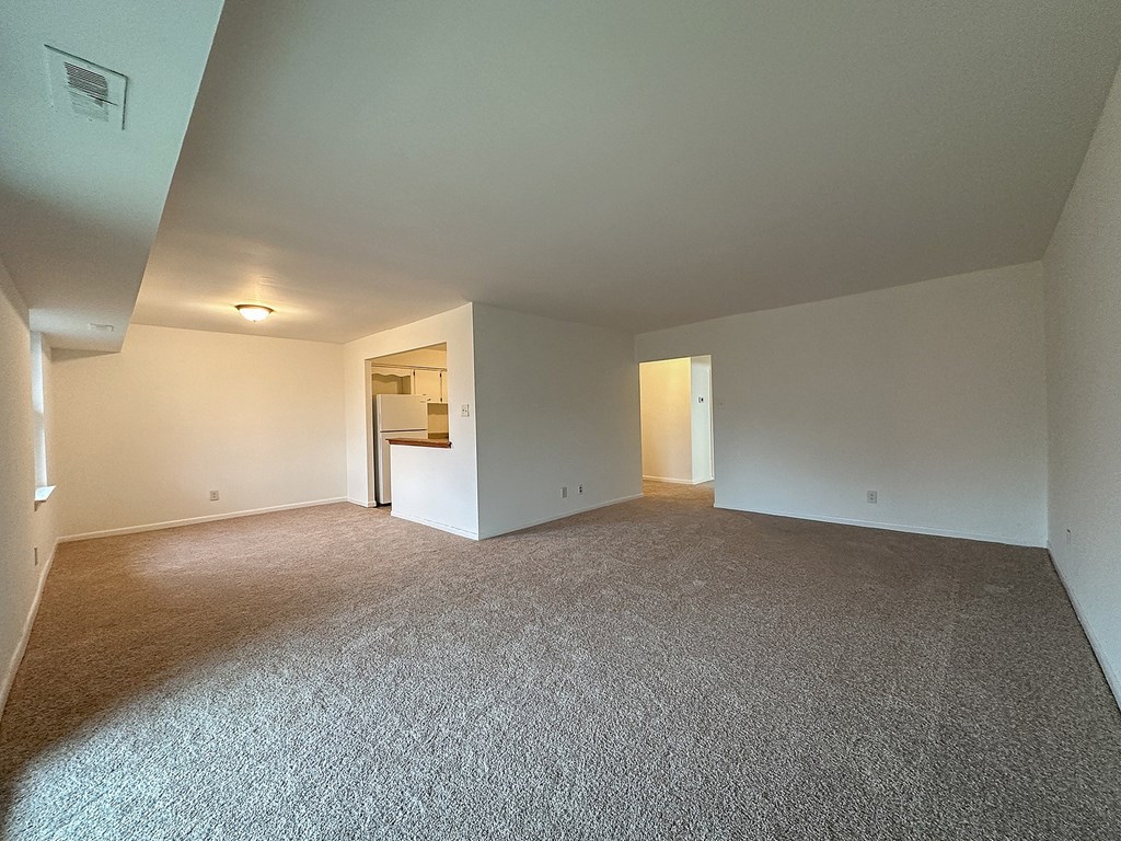 A spacious room with carpeted floor and white walls.