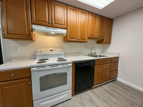 A kitchen with a white stove and wooden cabinets.