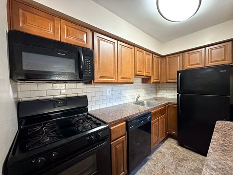 A kitchen with black appliances and wooden cabinets.