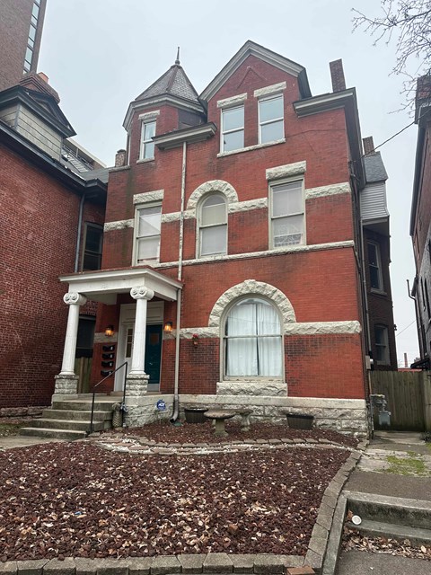 A red brick house with a green door and white columns.