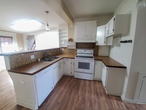 A kitchen with white cabinets and a brown countertop.