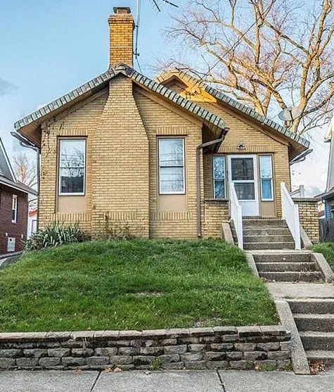 A small house with a brick exterior and a stone wall in front.