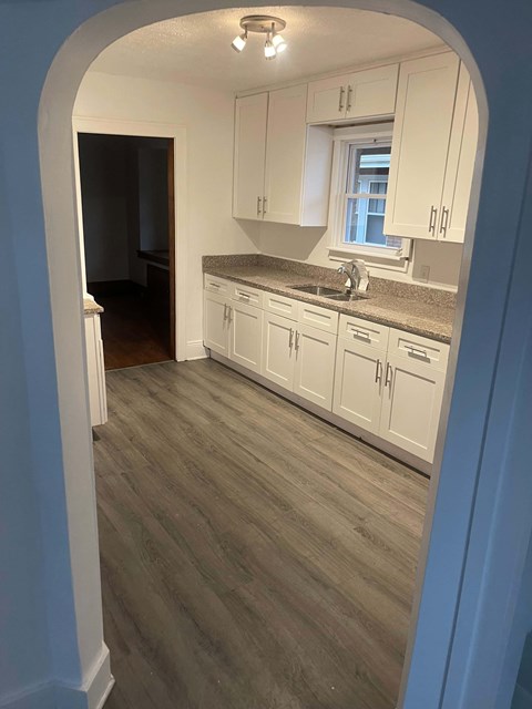 A kitchen with white cabinets and a window.