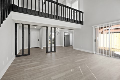 A spacious living room with a staircase and a large window.