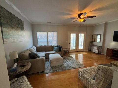 A living room with a grey couch, a chair and a ceiling fan.