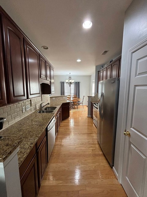 A kitchen with brown cabinets and a marble countertop.