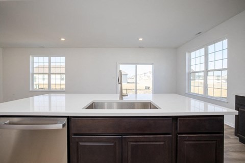 A kitchen with a white counter top and a stainless steel dishwasher.