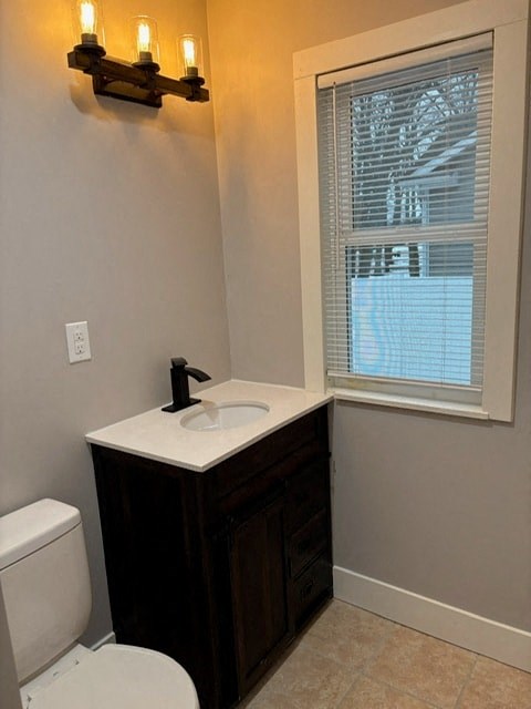 A bathroom with a sink, toilet, and window.