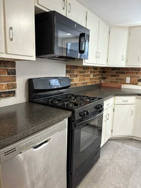 A black microwave is mounted above a black stove.