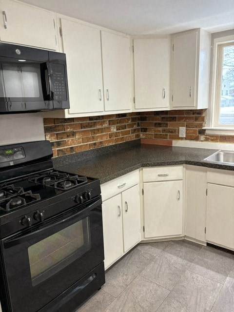 A kitchen with a black stove and white cabinets.