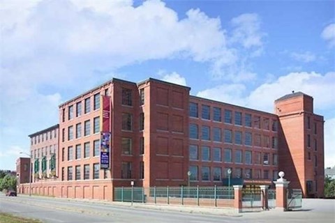 A red brick building with a green fence in front.