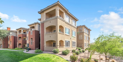 A large, multi-story residential building with a green lawn in front.