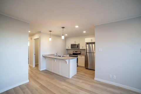 A kitchen with white cabinets and a wooden floor.