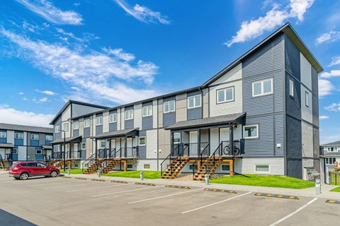A modern apartment building with a parking lot in front.