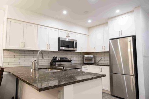 A kitchen with a black granite countertop and stainless steel appliances.