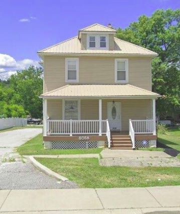 A yellow house with a porch and a sign that says "BOOK".