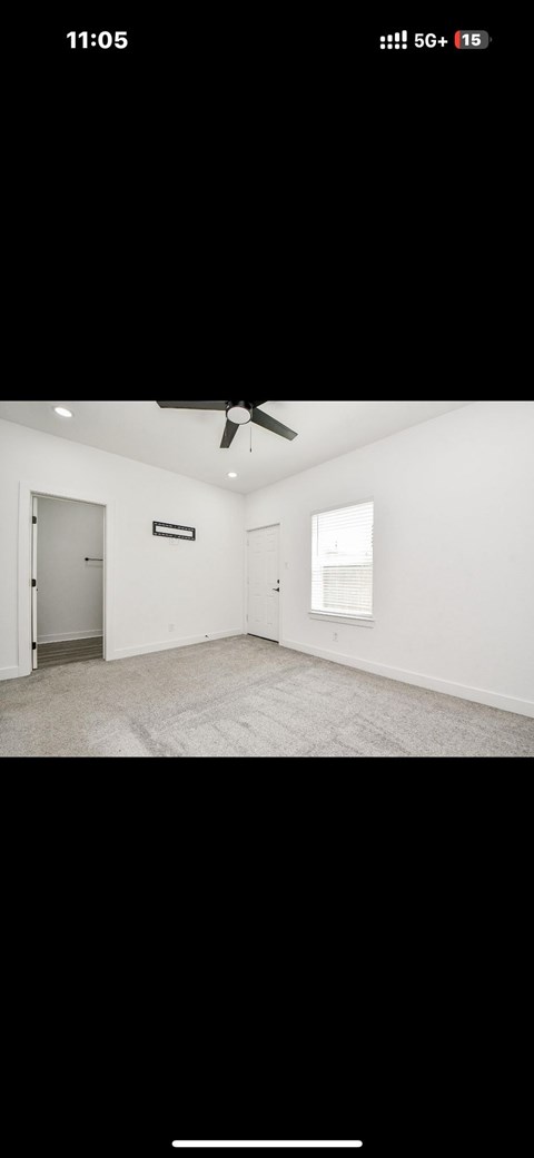 A room with a ceiling fan and a door.