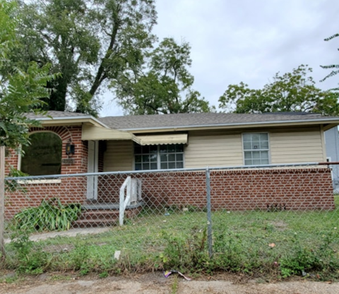 A house with a fence and a tree in front of it.