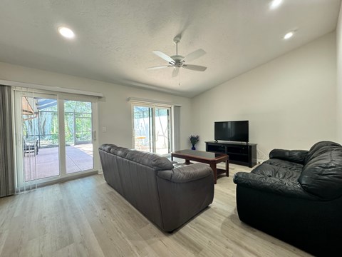A living room with a black couch and a television.