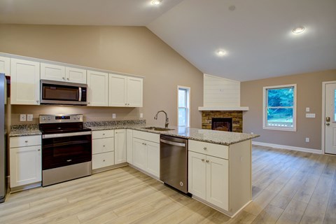 A kitchen with white cabinets and a wooden floor.