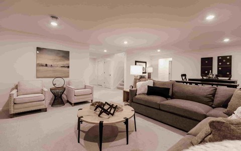 A living room with a brown couch and a painting on the wall.