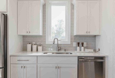 A kitchen with white cabinets and a stainless steel dishwasher.