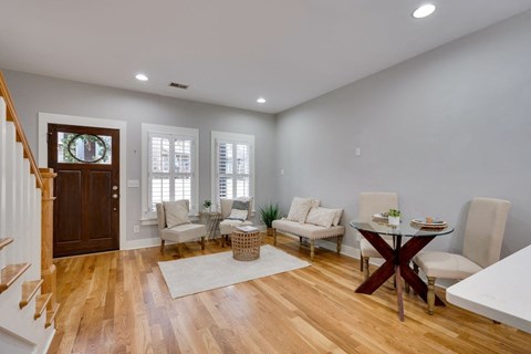 A living room with a wooden floor and a dining table set up.
