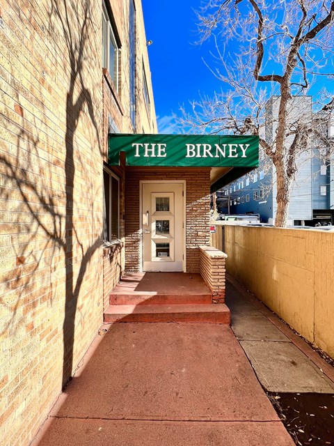 The Birney building has a green awning and a white door.